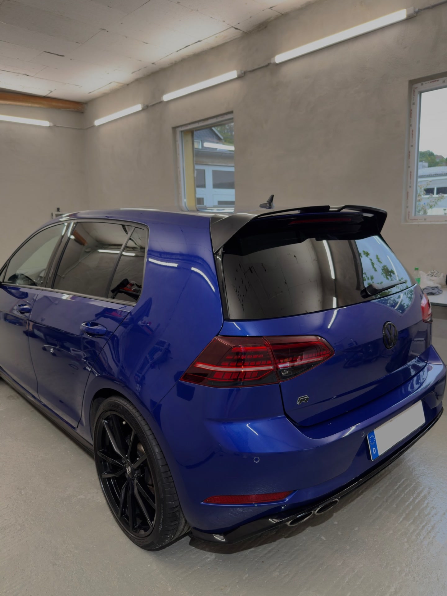 Blauer VW Golf R von schräg hinten in der hellen Werkstatthalle
