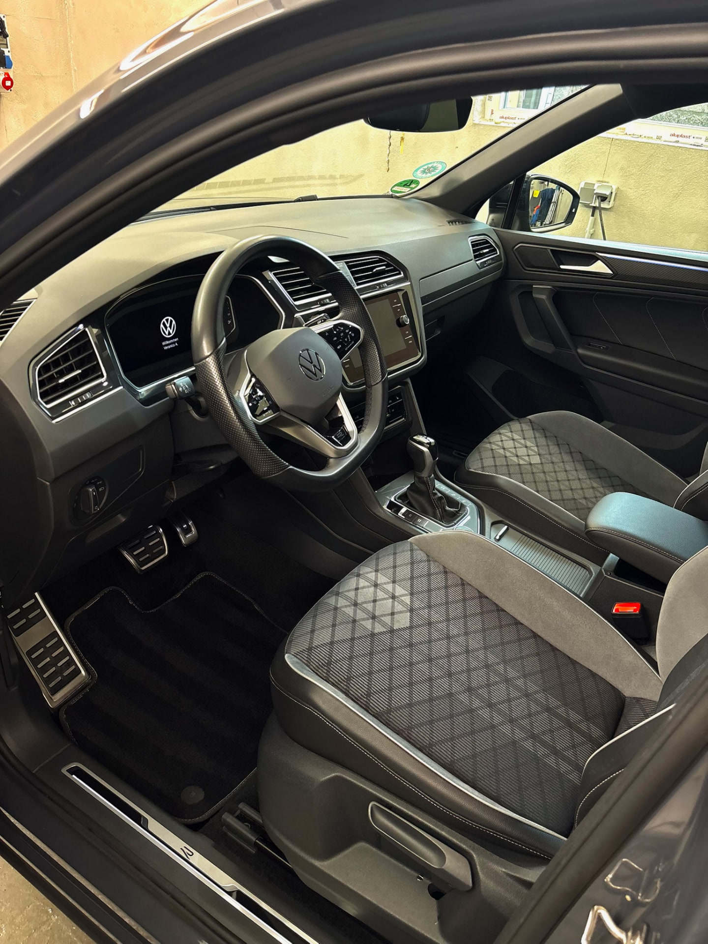 Cockpit des VW Tiguan mit Blick über das Lenkrad auf das Display und Alu-Pedale